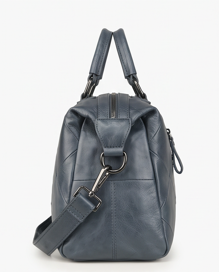A dark slate blue leather handbag shown from the side, featuring a top handle, a detachable shoulder strap, and silver-tone hardware, with the text 'SIDE & ATTACHMENT VIEW' at the bottom.