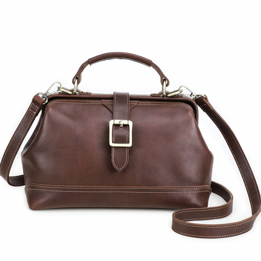 A dark brown leather handbag with a top handle, a buckle strap detail on the front, and a detachable shoulder strap, shown against a plain white background.