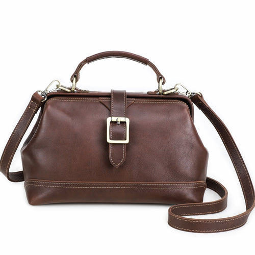 A dark brown leather handbag with a top handle, a buckle strap detail on the front, and a detachable shoulder strap, shown against a plain white background.