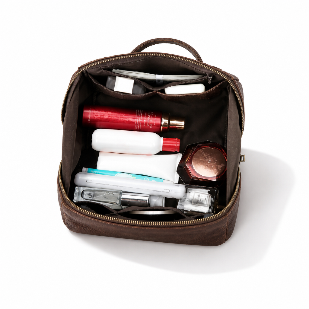 An open brown leather cosmetic pouch filled with various travel-sized toiletries and cosmetics, photographed from a top-down angle on a clean white background.