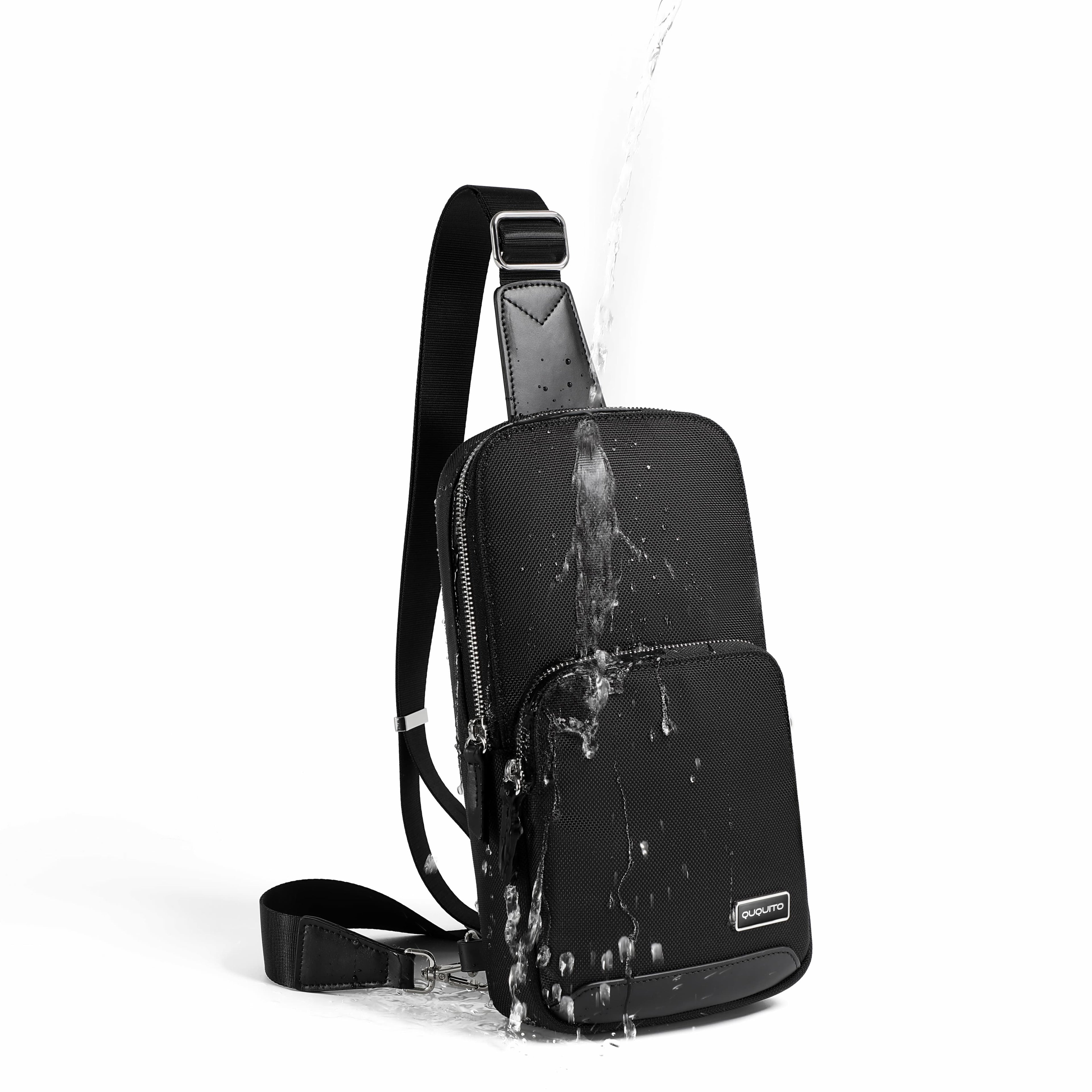 A black sling backpack with a water-resistant finish, shown with water splashing off it against a clean white background.