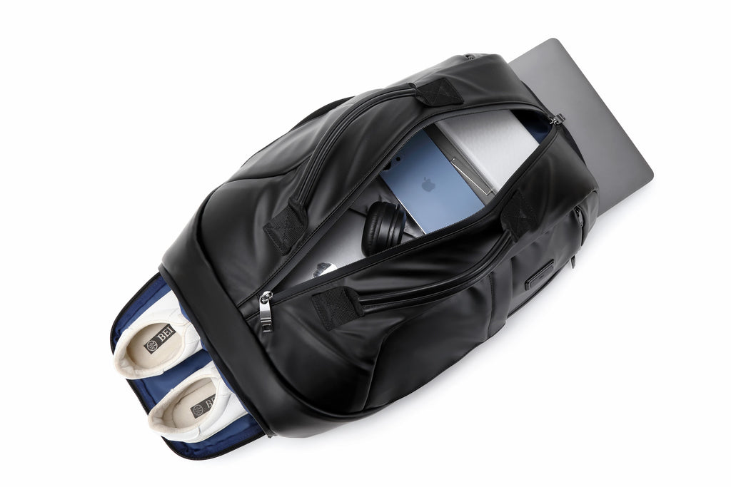 A black leather laptop and shoe bag shown open on a white background, with a laptop and headphones inside and a pair of white sneakers in a blue-and-white compartment.