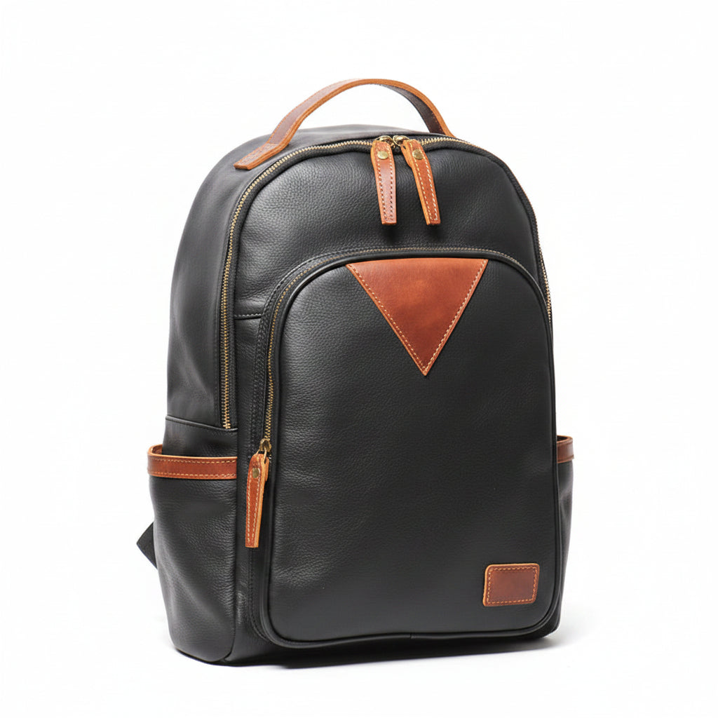 Black leather backpack with brown leather accents, including a top handle, zipper pulls, a side pocket, and a triangular accent on the front pocket,