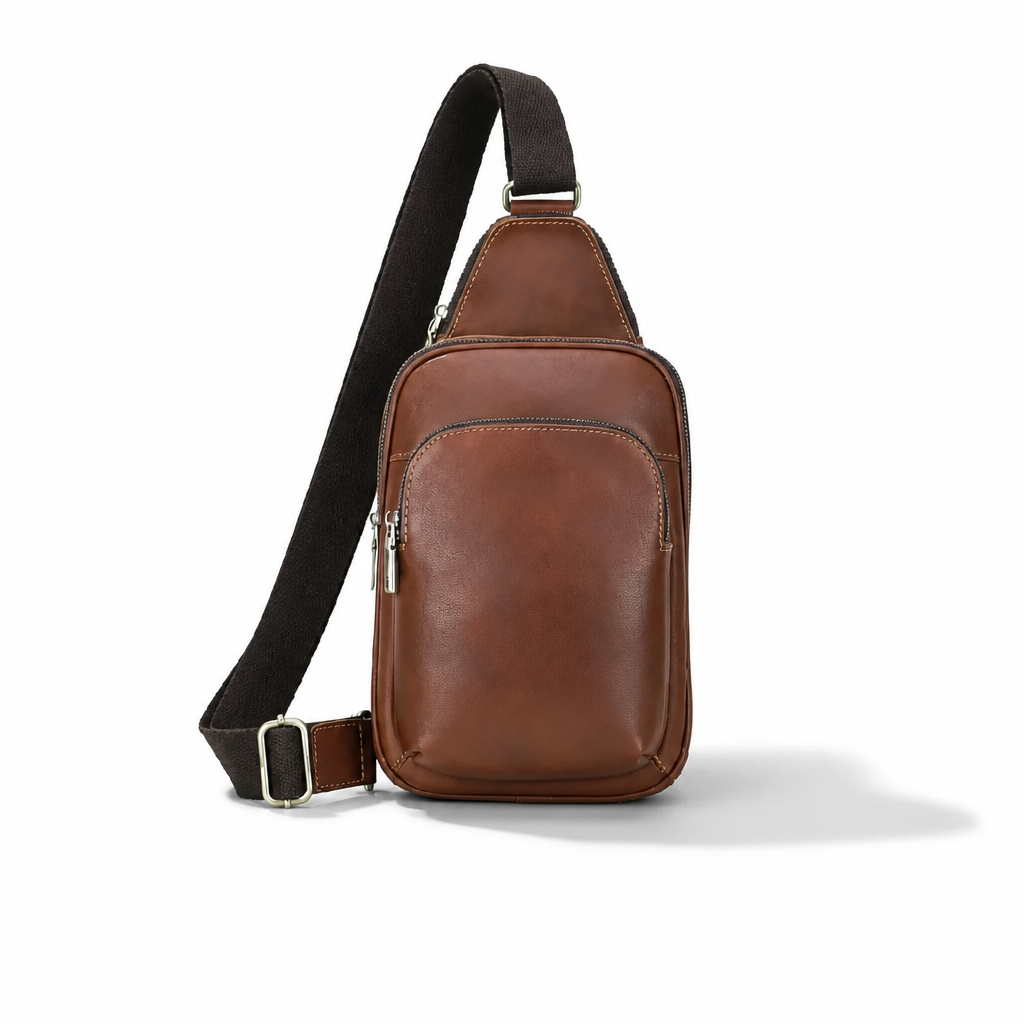 A brown leather crossbody sling bag with a black adjustable strap and silver-tone hardware, shown on a clean white background.
