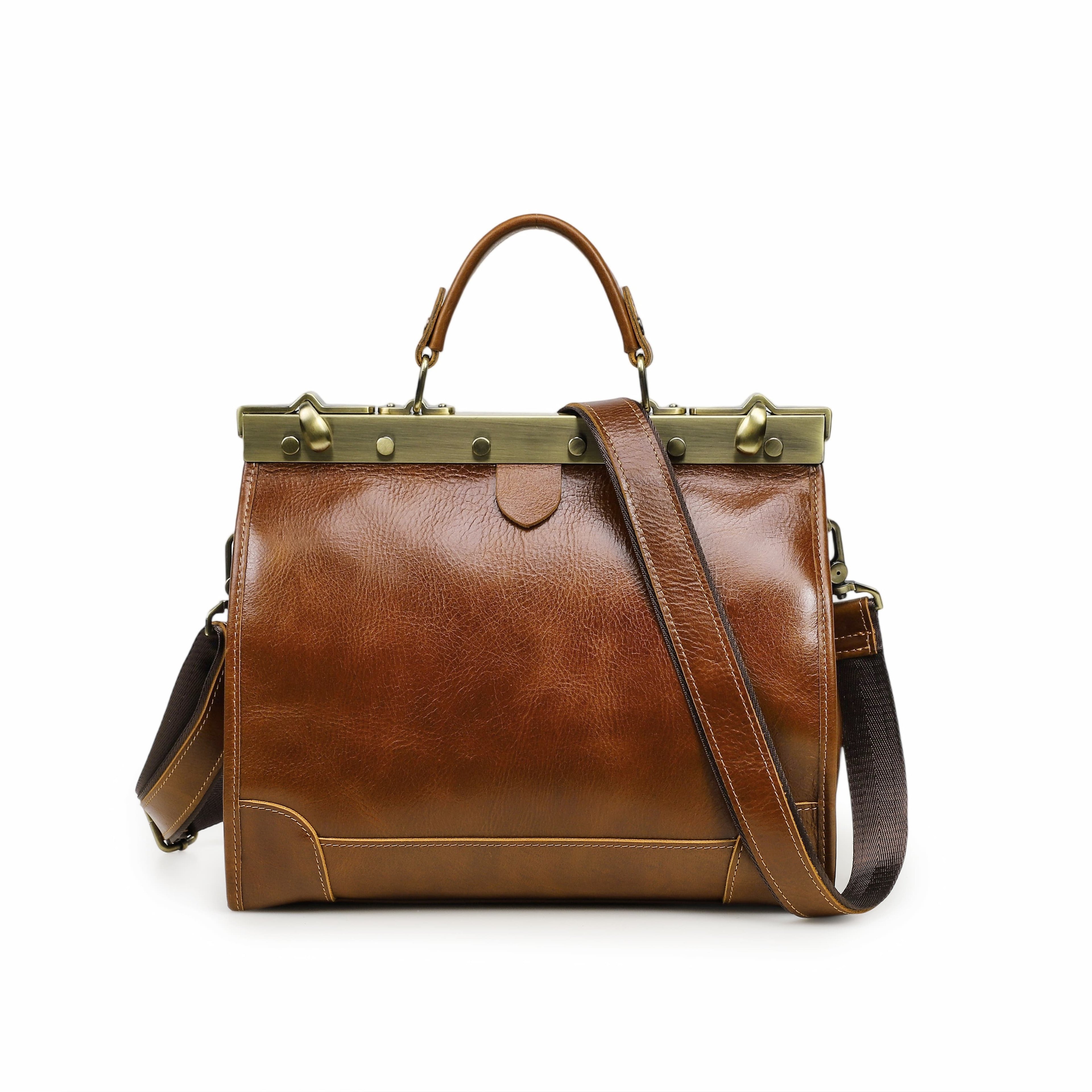 A brown leather satchel handbag with a top handle, adjustable shoulder strap, and a brass-tone metal frame on a white background.