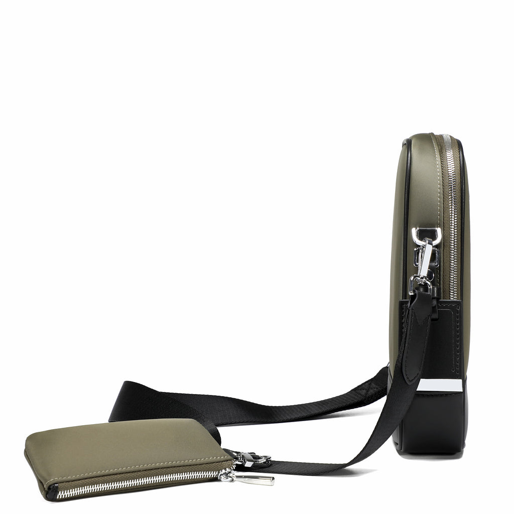 An olive green crossbody bag with a black strap and silver hardware, shown next to a matching zippered pouch on a white background.