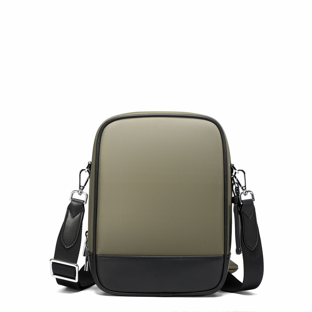 A rectangular crossbody bag with a muted olive green upper body and a black lower panel, featuring a black adjustable shoulder strap with silver metal hardware, shown against a plain white background.