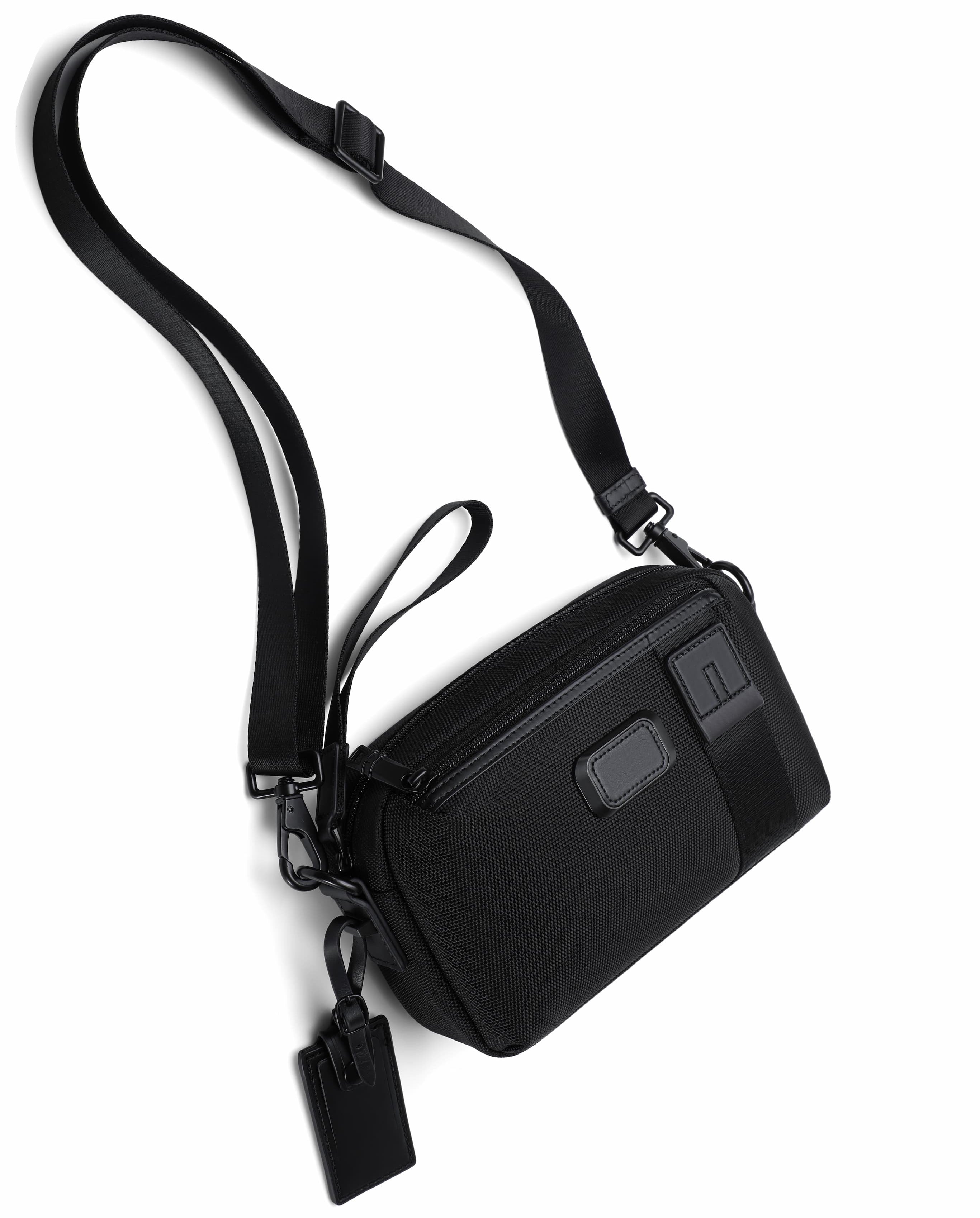A black nylon crossbody bag with an adjustable shoulder strap, a zippered main compartment, and a small hanging tag, shown on a plain white background.