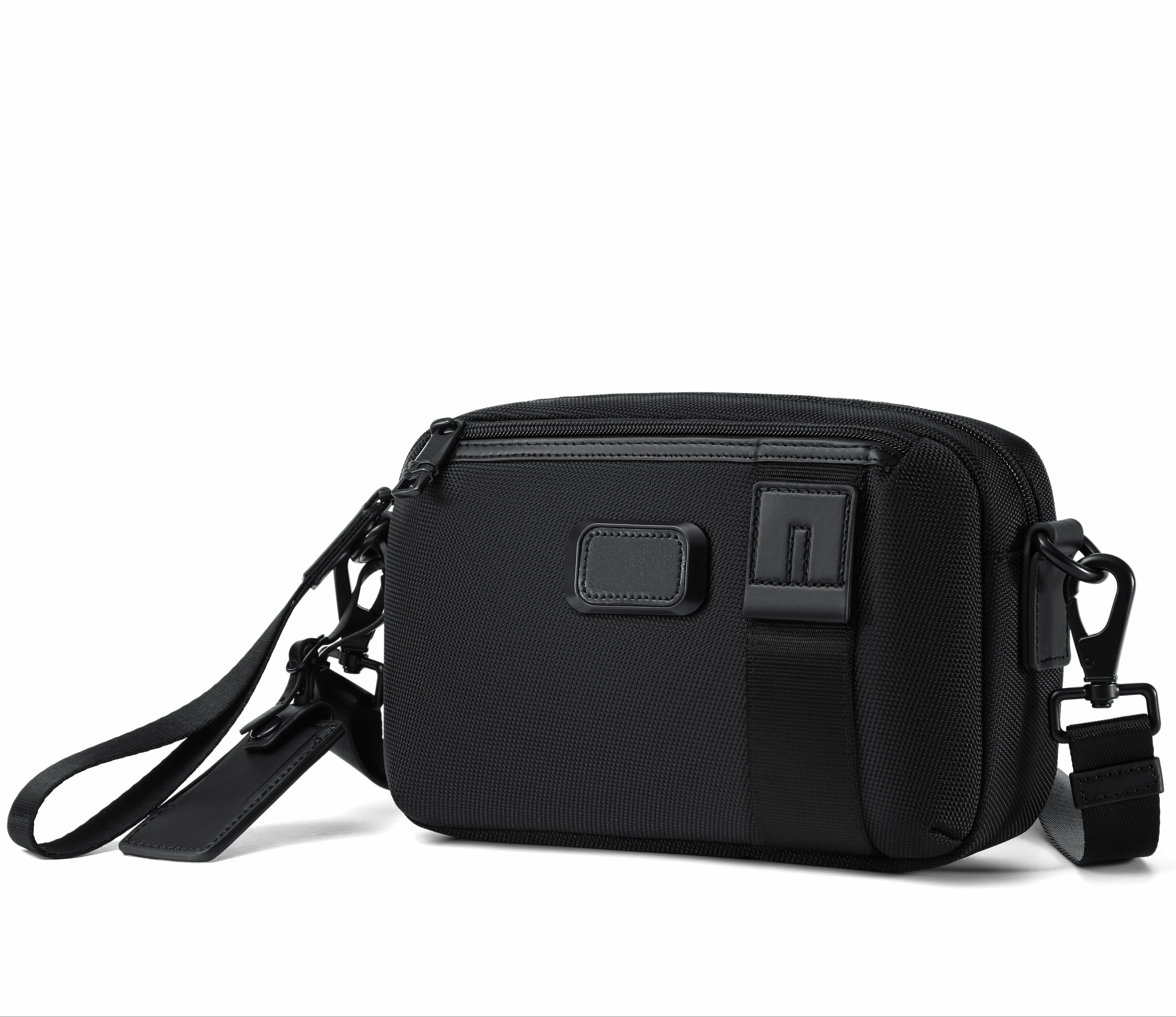 A black nylon crossbody camera bag with a matching black wrist strap and adjustable shoulder strap, shown on a clean white background.